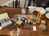 Photo showing collection of candles, candle holders, napkin holders, coasters and small decorative items on a wooden table.