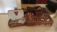 Wide view showing brown leather jewelry box open with compartments and small jewelry items, next to wooden jewelry organizer with mirror and cufflinks on top