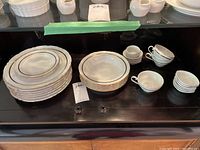 Full set of fine china dishes including plates, bowls, cups, and saucers arranged on shelf