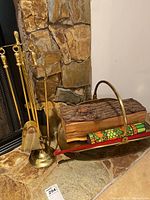 Full view of fire irons and log basket with wood logs for size reference at stone fireplace