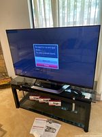 LG Smart TV on black init stand with three boxes of LG Cinema 3D glasses and manuals visible