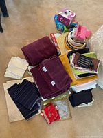 Various fabric linens including tablecloths, napkins, and placemats, along with paper plates and ziplock bags grouped on the floor.
