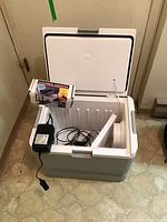 Opened Igloo plug-in cooler showing interior and Kool Mate power adapter inside.