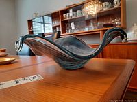 Side view of blue and black art glass bowl on wooden table.