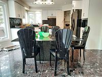 Six black wooden dining chairs arranged around a kitchen island, showing their overall design and condition.