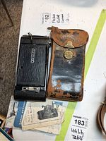 Kodak pocket camera with a well-worn leather case and multiple Kodak manuals beneath. Camera shows wear with metal and textured body.