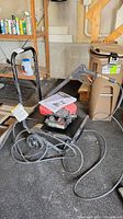Pressure washer and wand with cords lying on the floor in a garage setting
