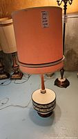 Full view of mid-century modern lamp with peach shade and teak and ceramic base.