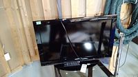Black Toshiba 32-inch flat panel TV on base stand, showing front and remote control on top.