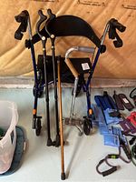 Front view showing blue Sidekick walker with four canes, one wooden and three metal with ergonomic handles