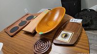 Photo showing wood serving boards, handmade bowl, wooden puzzle, and tile servers arranged on a table.