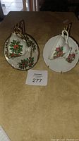 Photo showing two porcelain cup and saucer sets, one with holly leaf design and one with pink rose floral design, both made in Japan.