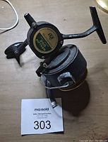 Side view of a vintage fishing reel showing the handle, spool and body with minor wear.