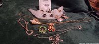 Photo showing assorted costume jewelry on a dark surface including bracelets, rings, necklaces, and pins of various designs and colors.