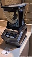 Front angled view of Ninja blender showing base, control buttons, transparent blending container with black lid, and handle.