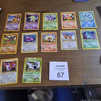 Top-down photo showing 12 older Pokémon cards laid out on a wooden table, including creatures like Abra, Drowzee, Nidorina, Aerodactyl, Ditto, Arcanine, and a Japanese Gyarados card.
