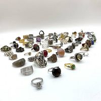 Wide view of assorted rings arranged on white surface showing variety of styles and stones