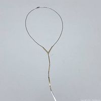 Full front view of necklace laid flat showing chain and lariat drop.