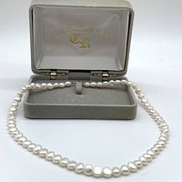 Pearl necklace displayed in open gray velvet box showing Tokyo Royal logo.