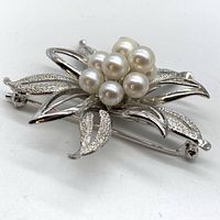 Side angle showing layered petals and pearl cluster of brooch pin