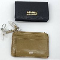Black Aimee Kestenberg wallet and tan Hobo zippered card holder laid flat on a white background showing front branding and design.