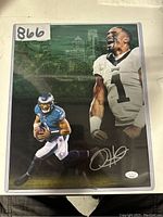 Front view of signed 11x14 photo in plastic sleeve showing two images of Jalen Hurts in Eagles uniform with silver signature.