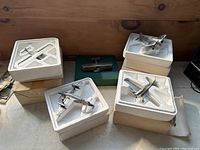 Five boxed die-cast airplane models displayed in custom styrofoam inserts on a wooden surface.