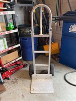 Front view of aluminum hand truck showing loading plate and wheels.