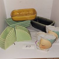 Overview image of six vintage ceramic and porcelain planters in various shapes and colors including a pair of light green fan-shaped, mustard yellow rectangular, dark green rectangular, and two porcelain lady head planters.