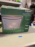 Front of box showing Hunter Ellipse bathroom fan with light and nightlight, model 90064, brushed nickel finish with frosted glass.