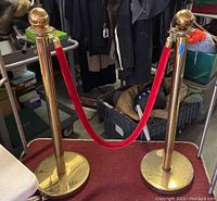 Two brass stanchions connected by a red velvet rope on a red carpet.