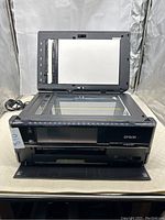 Front view of Epson Artisan 837 printer with lid open showing flatbed scanner glass and document lid.