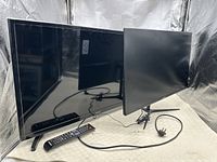 Front view of Samsung smart TV and flat screen monitor with remotes and cords shown clearly