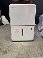 Full front view of the Toshiba dehumidifier showing water level indicator window and overall condition.