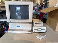 Front view of AppleColor RGB Monitor on top of Apple IIgs main unit, with external drives and mouse to the right