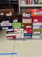 Pile of stacked shoe boxes showing various brands and sizes including Christian Siriano, Naturalizer, Grasshoppers, and more.