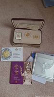 Collector's case containing gold coin, a gold stamped item, and paper certificates as well as booklets and coin cases related to Canadian Mint commemoratives.