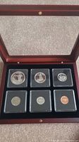 Full wooden display case with six Canadian Centennial coins in protective holders, arranged in two rows of three.