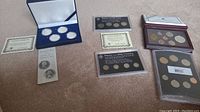Overview of coin sets and individual coins displayed with certificates and packaging.