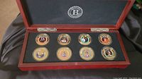 View of wooden display case with eight gold-plated Princess Diana legacy proof coins inside.
