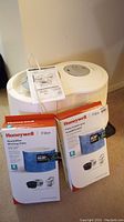Two boxed Honeywell replacement humidifier wicking filters placed in front of the humidifier with instruction manual on top.