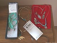 Full view of costume jewellery lot including turquoise bead necklace, feather pendant necklace, earrings, cufflinks, and starfish pendant necklace.