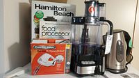 Lot contents showing all appliances: Hamilton Beach food processor with cookbook, Proctor Silex mixer in box, and Russell Hobbs kettle.
