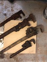 Four antique adjustable wrenches laid on a surface showing their range in size and condition.