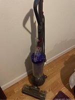 Full view of Dyson DC40 upright vacuum cleaner showing purple ball base and transparent dust bin.