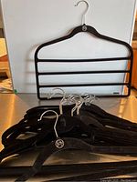 Multiple black velvet clothing hangers arranged flat showing the 'joy' logo on each.