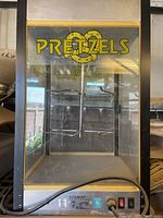 Front view of electric pretzel warmer showing metal prongs and pretzel graphic