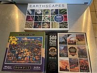 Four completed puzzles showing box covers: Earthscapes 500 piece, Golden Spike 500 piece, National Parks 500 piece, and Ravensburger 1000 piece Bird Village