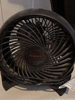 Front view of Honeywell black 10 inch desk fan showing protective grille and spiral blades with Honeywell logo center hub