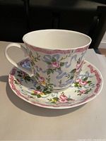 Fine bone china teacup on matching saucer with pink rose and blue ribbon pattern